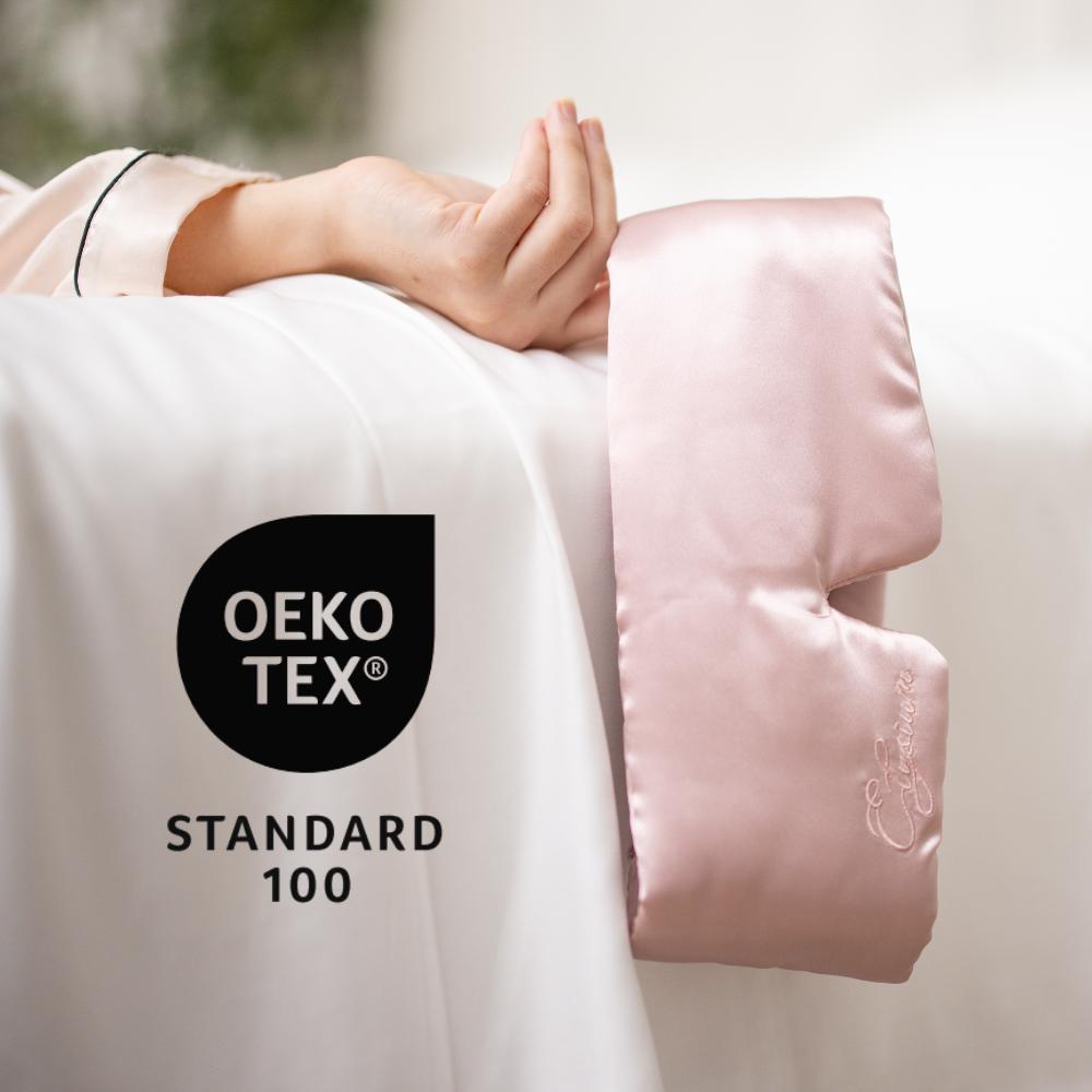 AnOEKO-TEX luxury eye mask in Pink draped from a woman's finger
