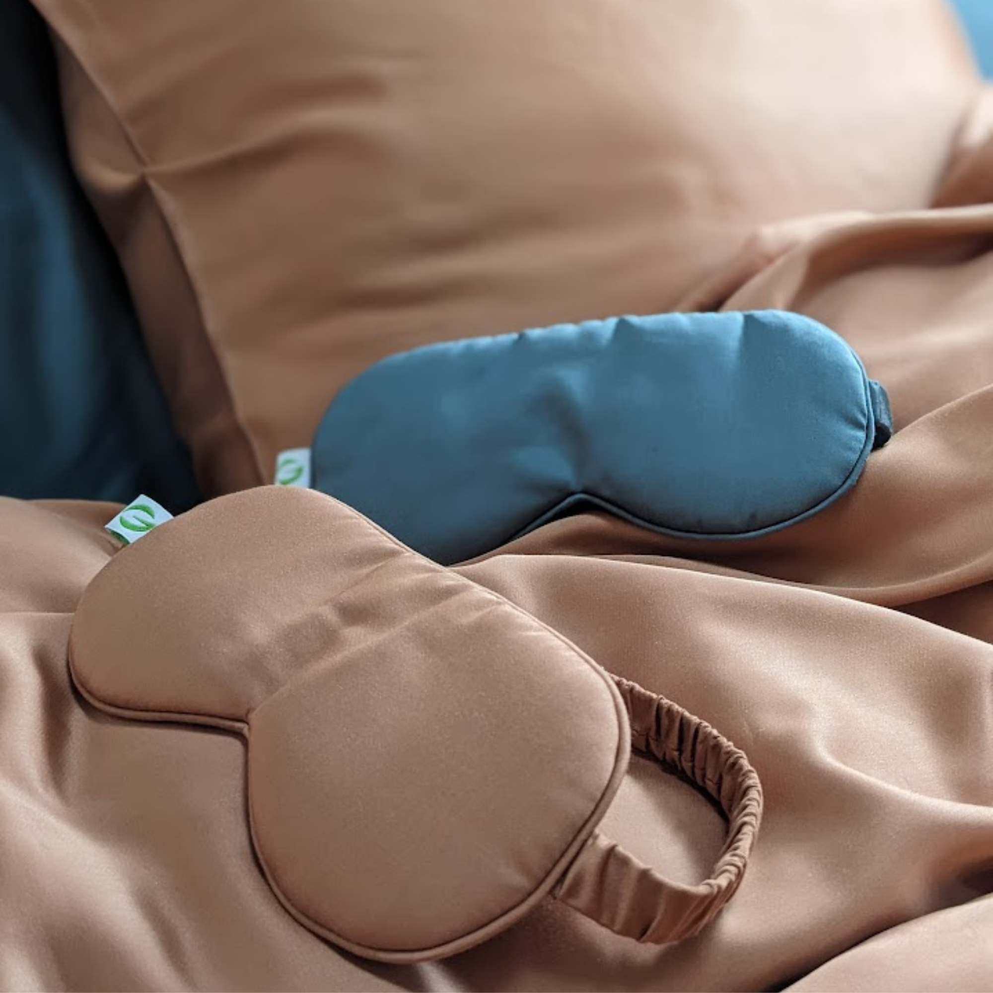 Brown and blue silk sleep masks on a bed