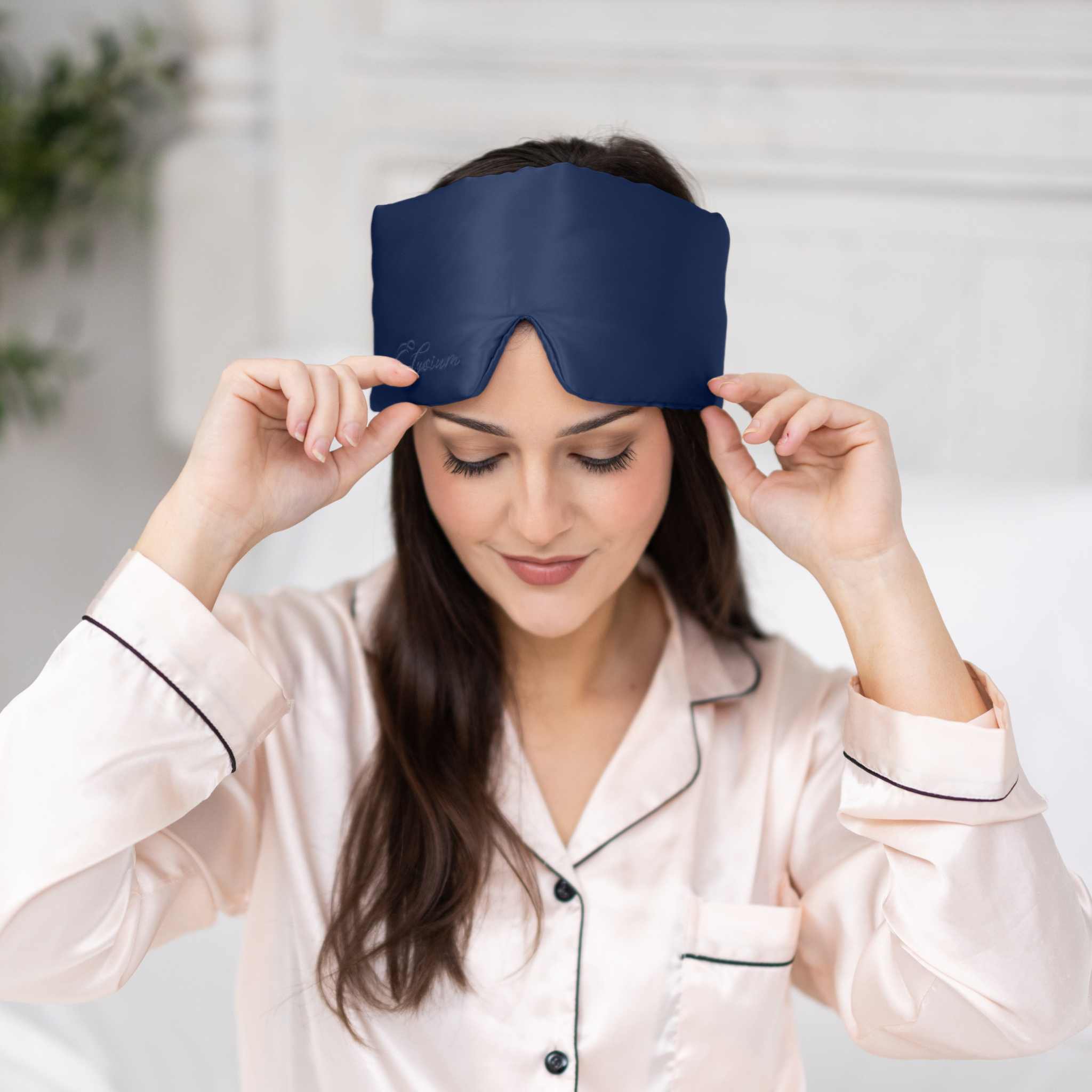 Young woman relaxing with Elysium Silk Eye Mask in Navy 