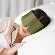 Young woman side sleeping in bed with Elysium Silk Sleep Mask in Avocado