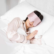 Young woman side sleeping in bed with Elysium Silk Eye Mask for eyes in Pink