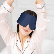 Young woman waking up in bed with Elysium Silk Eye Mask in Navy 