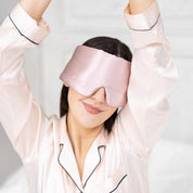 Woman stretching in bed with Elysium Silk Eye Mask for eyes in Pink