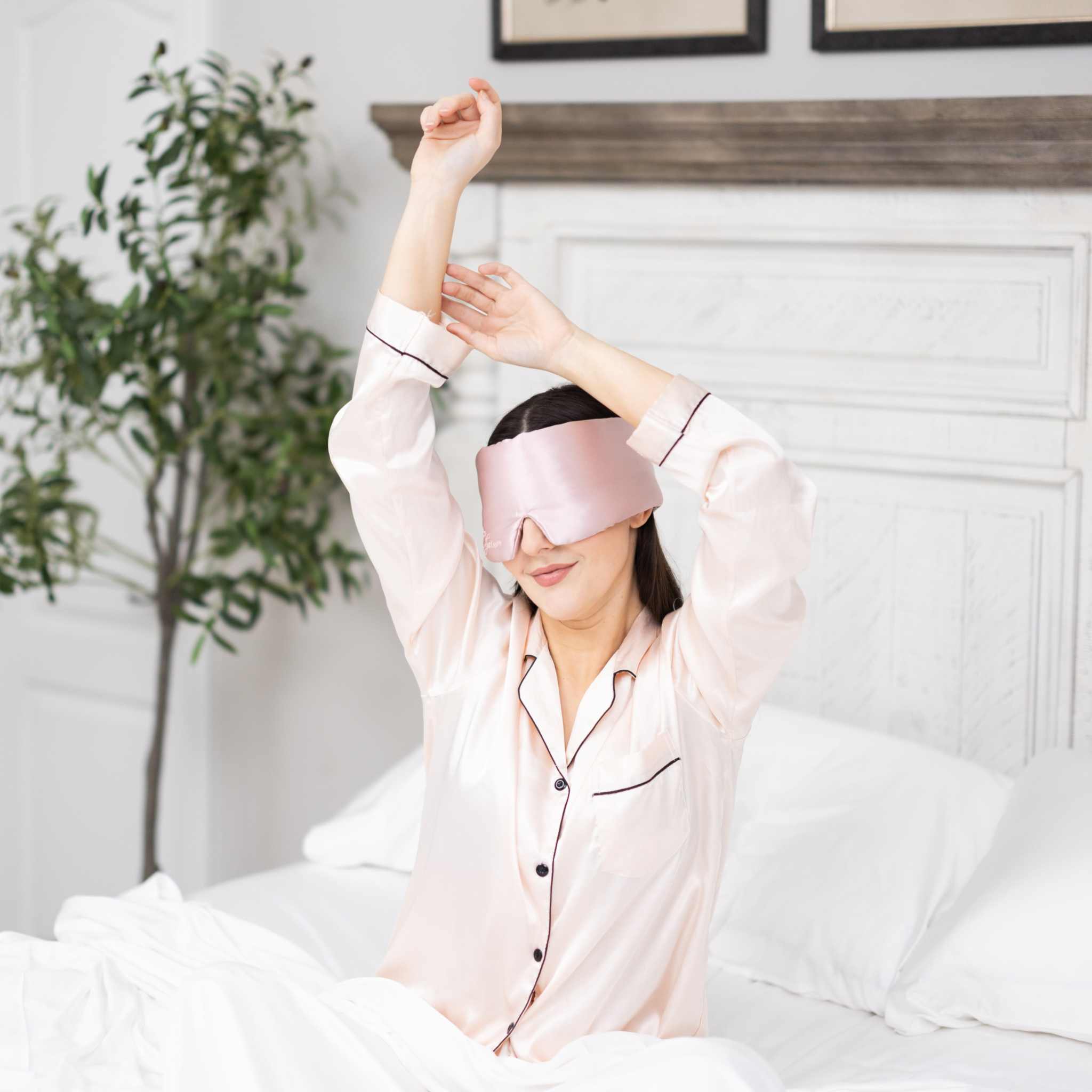 Young woman waking up in bed with Elysium Silk Eye Mask for eyes in Pink