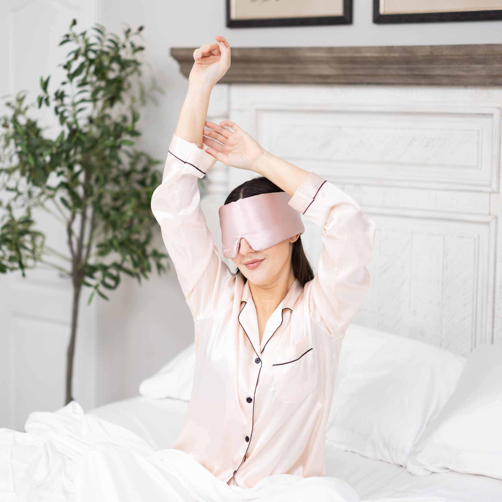 Young woman waking up in bed with Elysium Silk Eye Mask for eyes in Pink