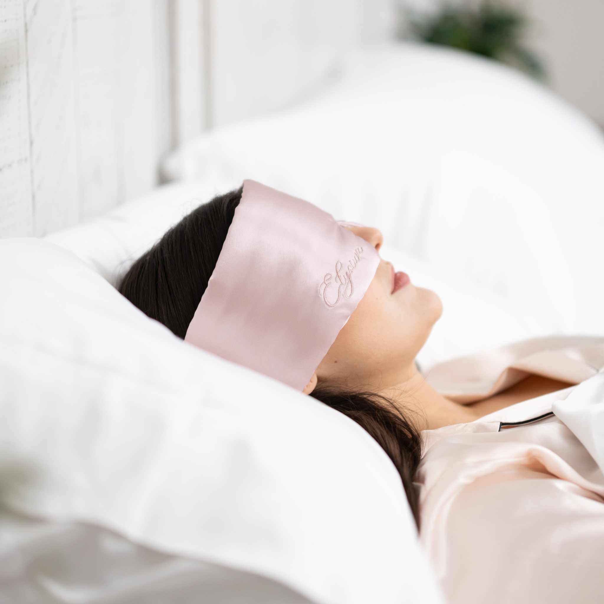 Woman sleeping with Elysium Silk Eye Mask for eyes in Pink