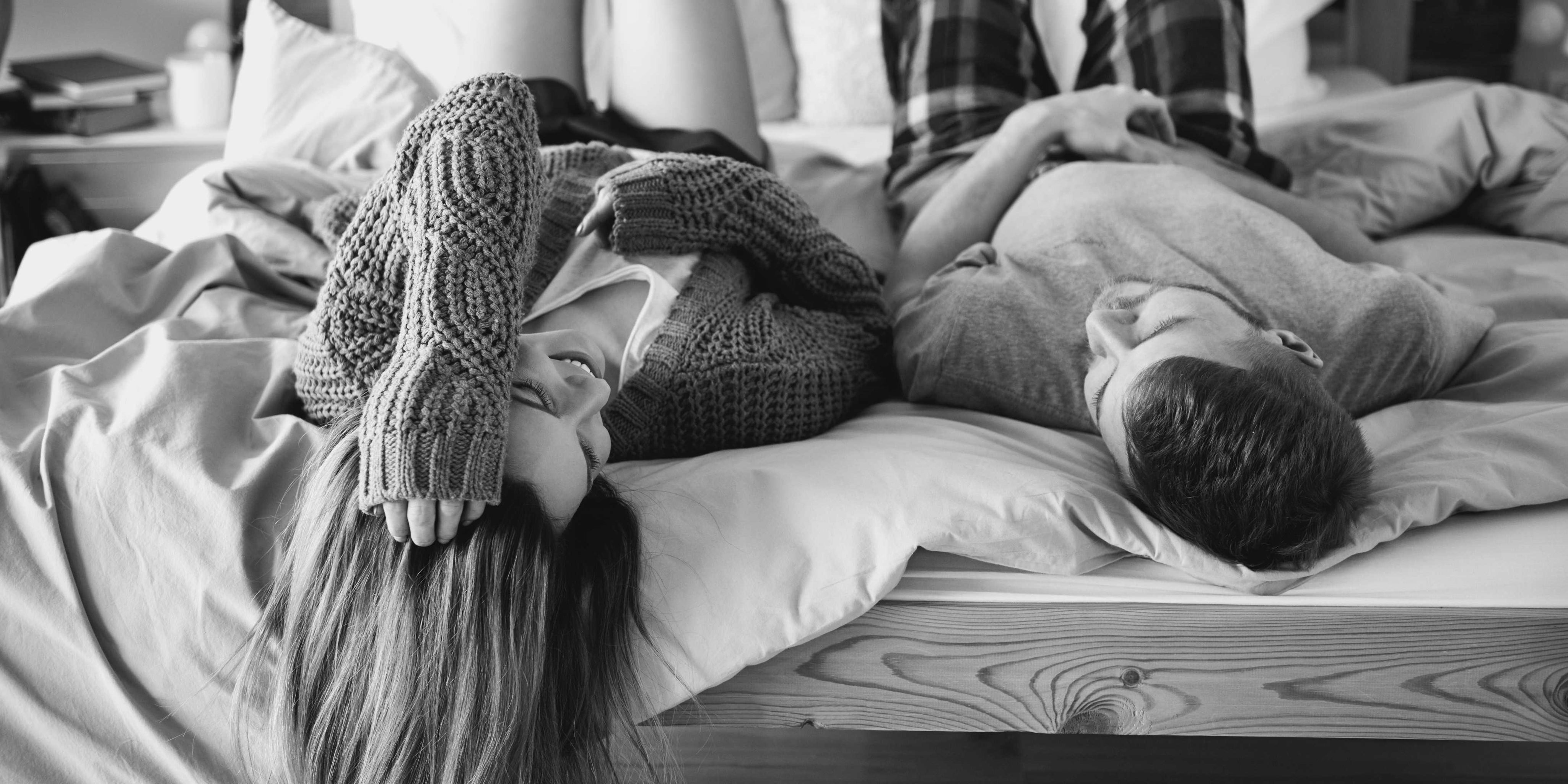 a young couple laughing together while laying on bamboo bed sheets